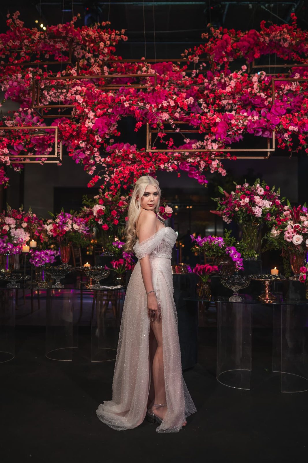 Aniversariante de 18 anos em vestido claro sob teto suspenso de flores pink em festa assessorada por Dani Baida