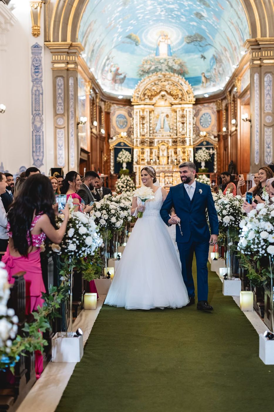 Noivos saindo da igreja entre convidados em casamento assessorado por Dani Baida