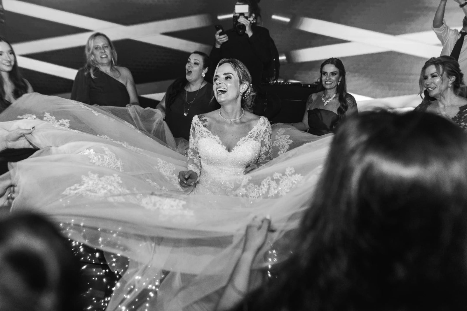 Noiva sorrindo na pista com o vestido estendido pelas madrinhas em casamento assessorado por Dani Baida