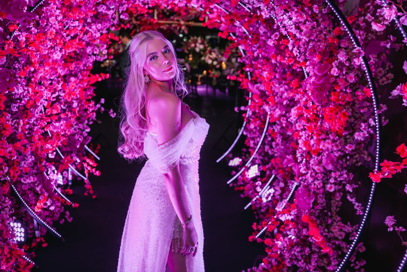 Aniversariante de 18 anos em portal circular de flores de cerejeira em festa assessorada por Dani Baida